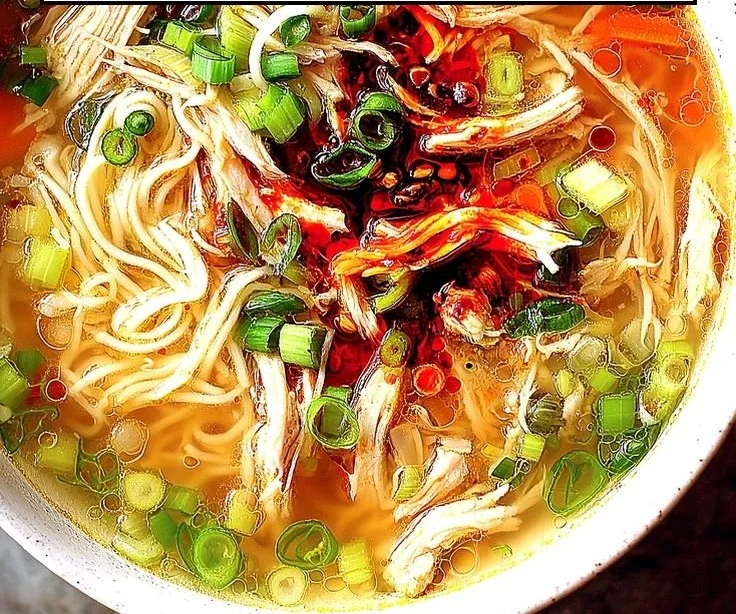 Bowl of classic ginger garlic chicken soup with noodles and herbs